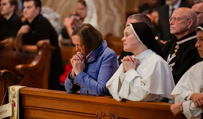 Dominican Sister in a church with other Catholics praying.