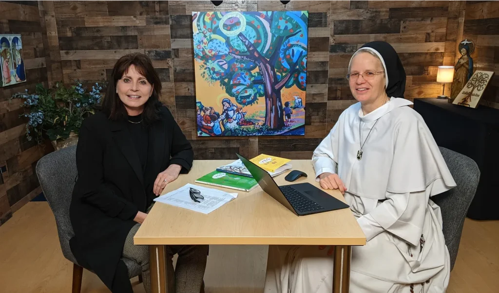 Dr. Karen Villa, a licensed clinical psychologist with over 30 years of experience in adult and child psychotherapy, and Sr. John Dominic Rasmussen, a Catholic school teacher and principal, sit at a table discussing holistic Catholic education through Catholic mental health resources, Catholic social-emotional learning, faith-based neurobiology, and Catholic parenting tools. The program supports grace-filled relationships for Catholic families.