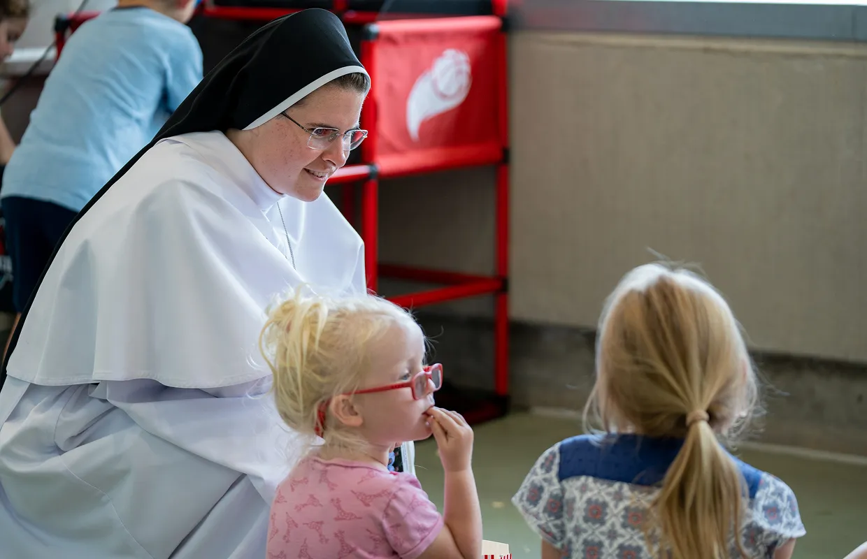 A Dominican sister sits on the floor with two young girls, developing a secure relationship through Catholic social emotional learning, otherwise known as Catholic SEL.